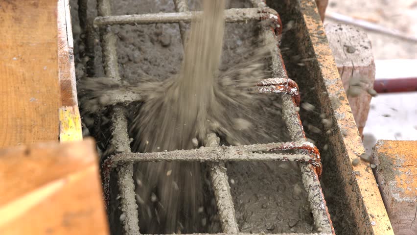 Construction workers with concrete boom pump crane at new house construction site pouring concrete into a formwork with reinforcement for building walls, slow motion