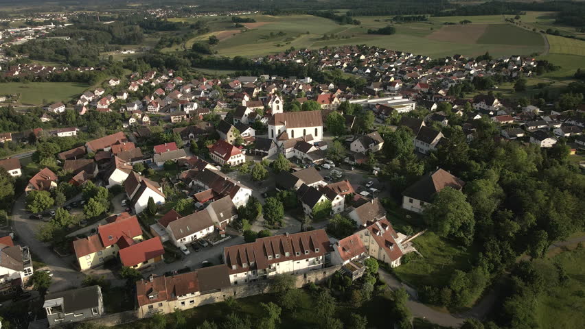 Drone footage revealing the historic hilltop town of Aach in Baden-Württemberg. As the drone ascends, it showcases the charming old town and the surrounding village below.
