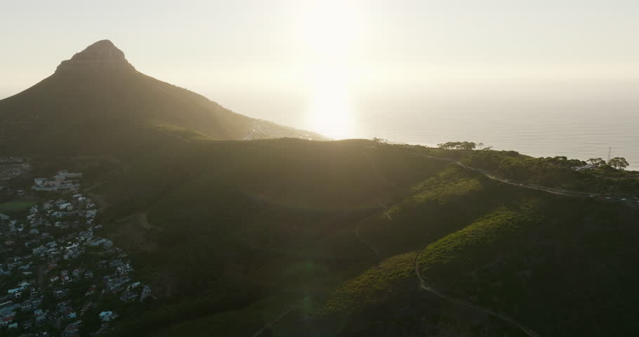 Establishing aerial view of Cape Town at sunset with Lions Head Peak, surrounded by ocean and city districts. Majestic and scenic landscape in South Africa. 4K scenic panoramic left drone shot