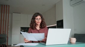 Smiling latin hispanic young business woman working on laptop computer reading financial bills document at home office. Accountant entrepreneur manager businesswoman doing paperwork using pc remotely - Powered by Shutterstock - Get 15% off with code: PIKWIZARD15