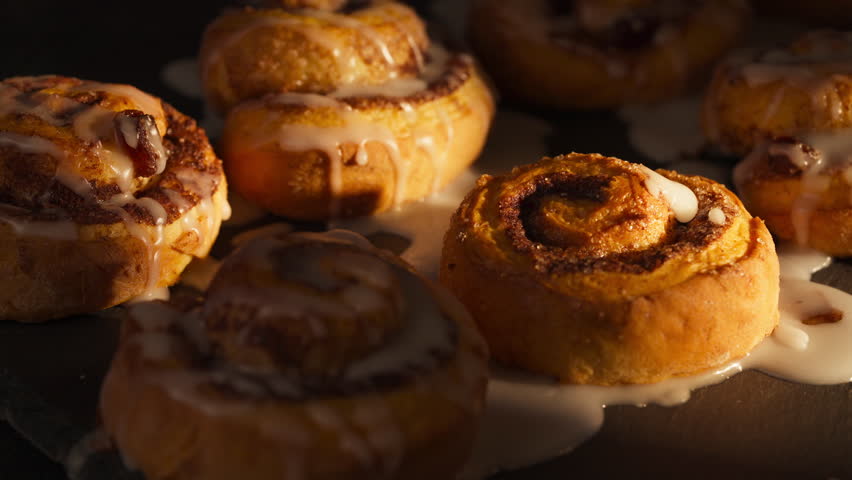 Drizzling Icing On Top Of Cinnamon Rolls. - closeup shot