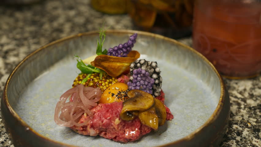 Green Olive Oil Dripping Onto Plate Of Steak Tartare At Fine Dining Restaurant. closeup shot
