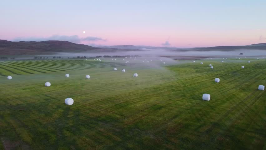 Foggy morning in the Icelandic countryside of Borgarfjörður. Panoramic view of the freshly harvested hay laid out to dry on the field