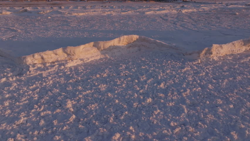 Frozen Lake Huron with snow-covered surface and ice formations at sunset