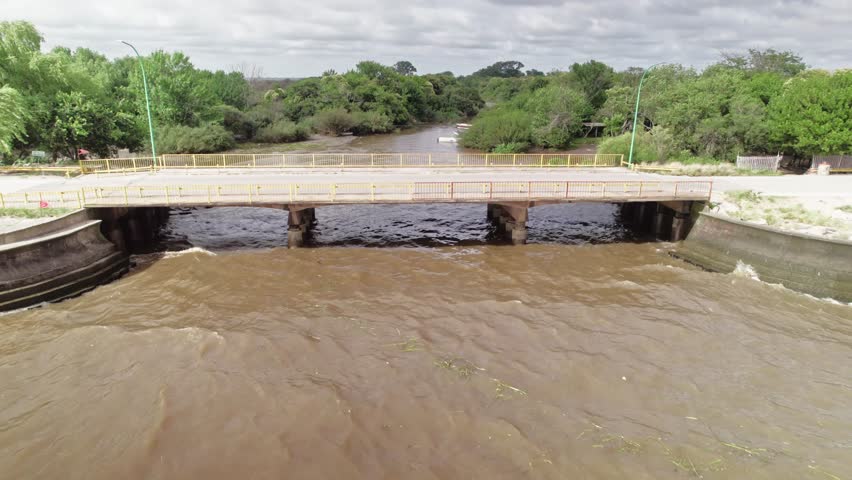 Drone footage capturing a bridge over the Rio de La Plata, with lush green trees along the riverbanks.