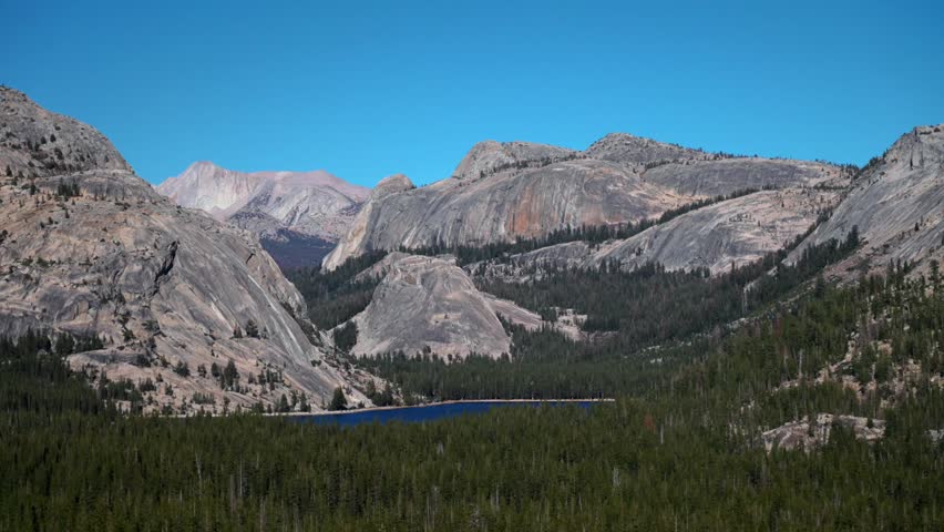 Tioga Lake Pass Yosemite National Park West Portal entrance wilderness forest rugged rocky formation terrain California Lee Vining forest sunny blue sky clouds Sierra Nevada Mountains landscape static