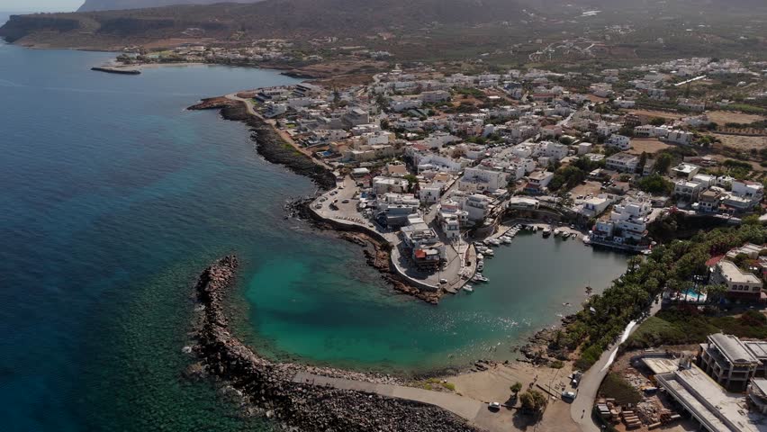 Aerial - scenic Sissi Bay with vibrant village and turquoise waters in Crete Greece