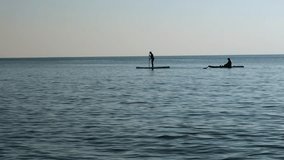 Couple on sup boards swim along the beach. Silhouette of a woman and a man paddling on their SUPs on a river. Paddle boarding on the sea. - Powered by Shutterstock - Get 15% off with code: PIKWIZARD15