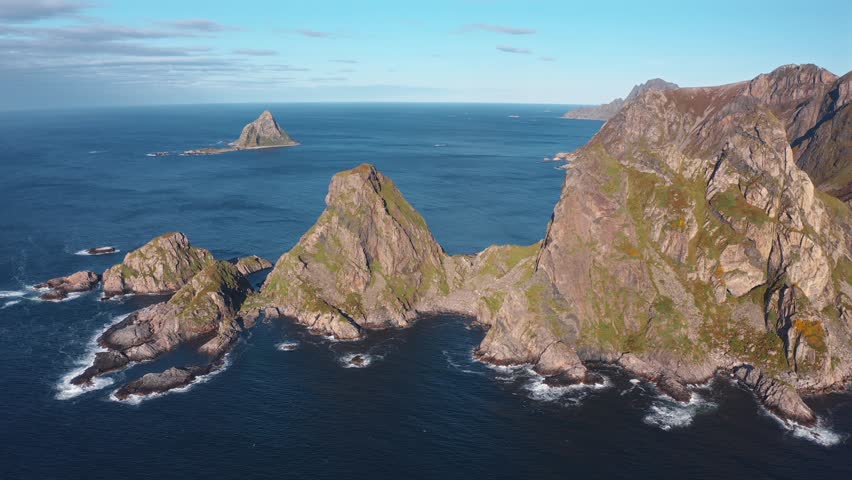 Aerial shot of rugged mountains by the sea, showcasing the dramatic Måtinden peaks