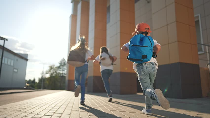 Pupils walking school with backpacks. Excited children first school day. Back to school scene with pupils carrying backpacks. First day at school for pupils. Children with backpacks heading building.