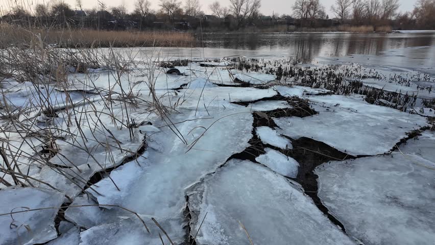 Winter landscape with ice on the river. Cracked ice on the lake. Frosty winter landscape. Frozen trees in ice. Flooded and frozen ground. Birds on ice. 