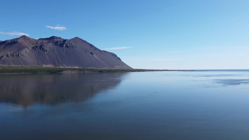 Mount Hafnarfjall, landmark of the western region of Iceland and part of an extinguished volcano, reflecting into the surrounding ocean. Beautiful composition in shades of blue