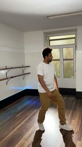 Young male dancer performing dynamic afro hip hop choreography, practicing intricate moves with passion and energy in bright, spacious dance studio