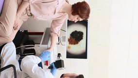 Male doctor examines neoplasms or moles on the woman patient's skin - using special apparatus for dermatoscopy digital dermoscope. Prevention of melanoma and skin cancer. World Cancer Day	 - Powered by Shutterstock - Get 15% off with code: PIKWIZARD15