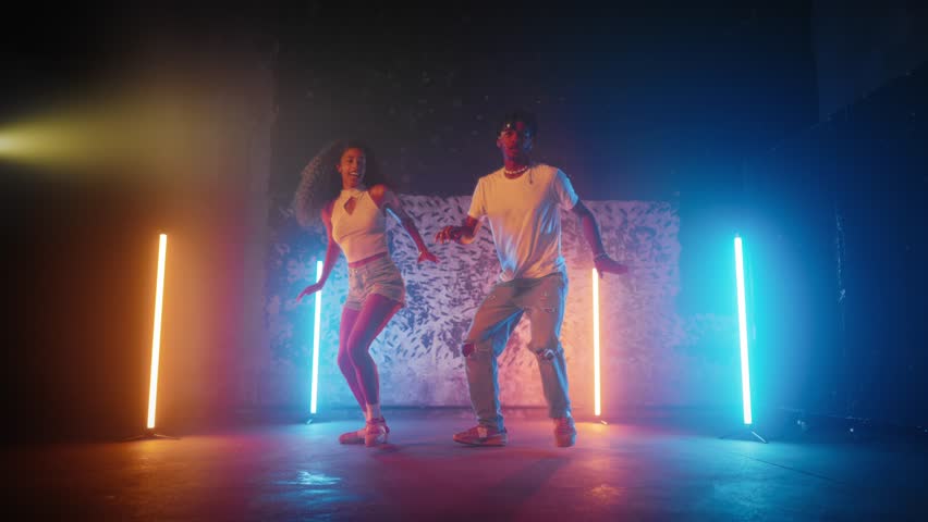 People dancing reggaeton and dancehall in dance studio, black man and woman. Active dance performance, African American dancers performing modern choreography, street style dance, slow motion shot