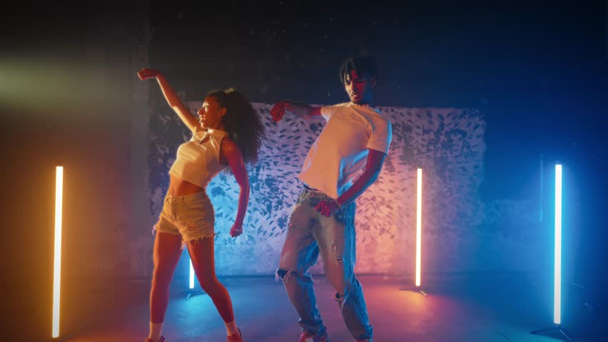 Dance and energy, portrait of couple of African American dancers in studio. Joyful pair of dance performers enjoying music in dance party, street style and contemporary choreography, medium shot