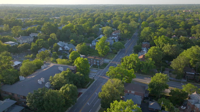 Aerial panning shot showcasing the charming Clayton neighborhood and bustling cityscape in St. Louis, Missouri. Captured on a beautiful clear day, highlighting residential charm, and vibrant greenery