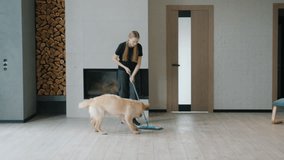 Teenage girl playfully dancing with a mop while cleaning, as an energetic Golden Retriever joyfully runs around in a modern living room. High quality 4k footage - Powered by Shutterstock - Get 15% off with code: PIKWIZARD15