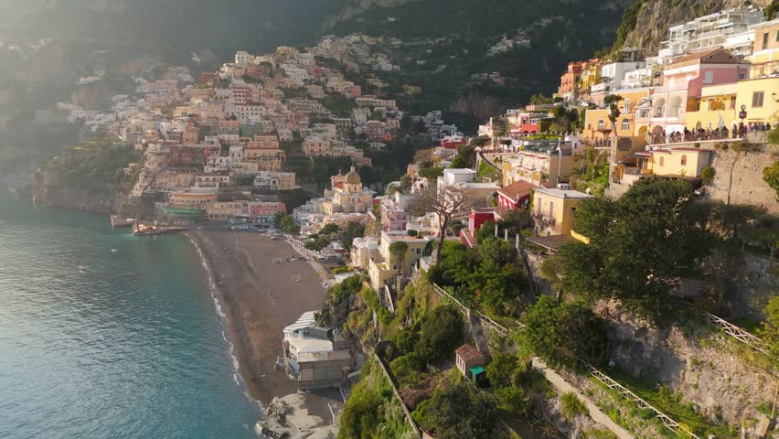 Epic shot of colorful village Positano, Amalfi coast, Italy. Fly over colorful houses, church and beach in Positano at sunset