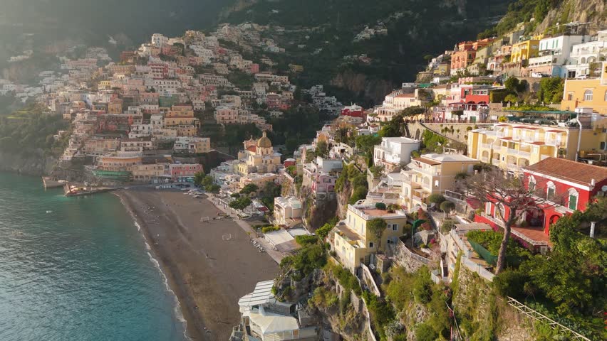 Epic shot of colorful village Positano, Amalfi coast, Italy. Fly over colorful houses, church and beach in Positano at sunset