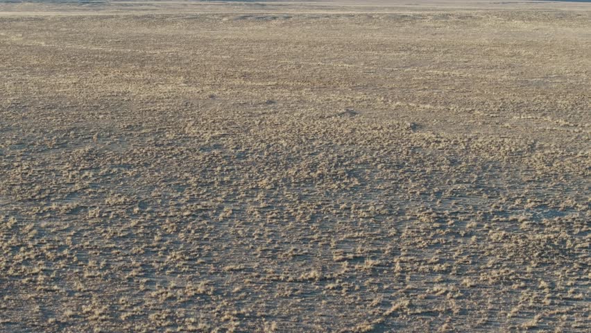 A low to the ground, slow-rising 70mm drone shot of the sacred “Ship Rock”, a massive, monolithic monadnock towering above the high-desert plain of the Navajo Nation, in New Mexico, United States.