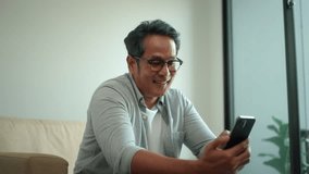 Happy asian senior middle aged man enjoy using smartphone while sitting on sofa in living room at home, elderly man with mobile phone for social web application online. 
 - Powered by Shutterstock - Get 15% off with code: PIKWIZARD15