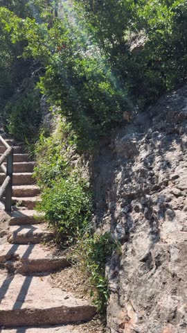 Walking in the mountains of Montserrat in Spain in summer. Panorama of mountain peaks and green plants against the blue sky. Trails for active recreation