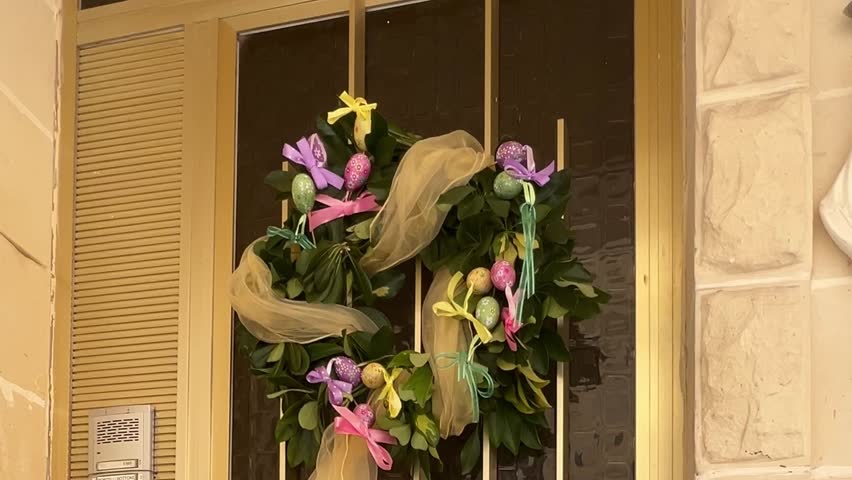 Decorative round Easter decoration with painted Easter eggs and colored ribbons for the front door of the house.