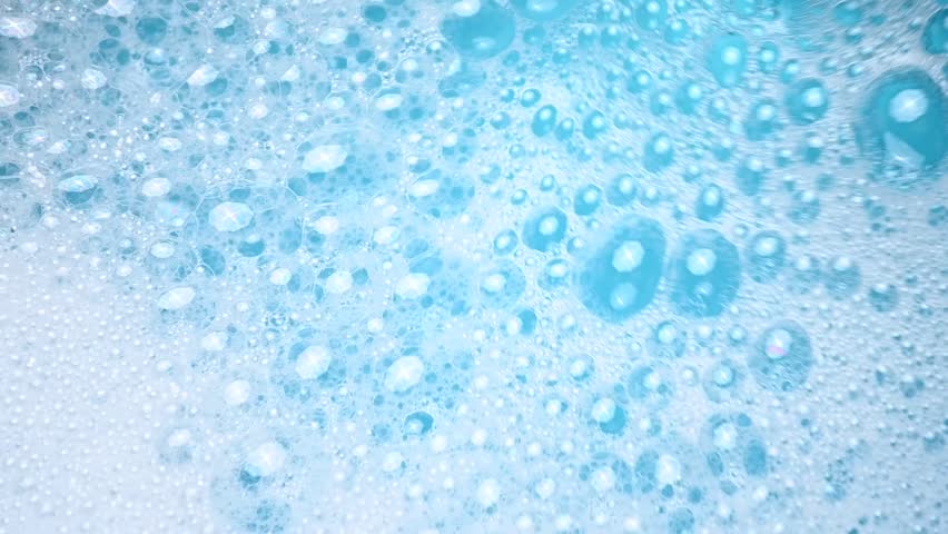 White soap foam float in water. Concept of cleaning and washing. Abstract soap suds moving in a circle.
