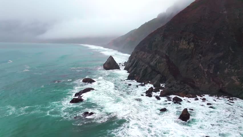 Rugged dramatic untouched coastline large surf waves USAL Beach campground aerial drone California PNW Lost Coast Trail cloud layer mist rain fog morning boulder rocks nature landscape circle right