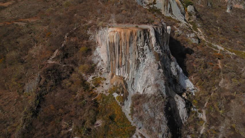4K drone footage of Hierve el Agua, Oaxaca, ascending with a wider view over petrified waterfalls, natural pools, and semi-desert vegetation, offering a breathtaking perspective for travel projects.
