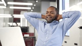 Happy african american businessman finished work on laptop while sitting at workplace in business office. Smiling satisfied black man puts his hands behind his head, leaning back in chair. Work done - Powered by Shutterstock - Get 15% off with code: PIKWIZARD15