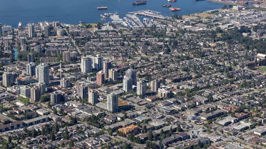 Aerial view of North Vancouver, BC, Canada, featuring buildings, harbor, and cityscape on a sunny day.