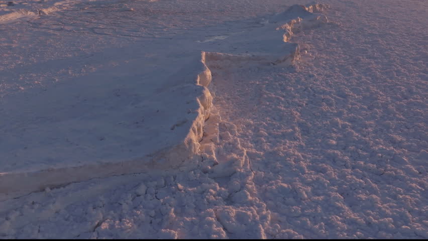 Frozen expanse of Lake Huron with snow and ice formations at golden hour