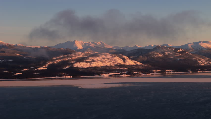 Gray Clouds Above Snowy Mountains On Shore Of Lake Laberge At Sunset In Yukon, Canada. wide shot