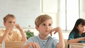 Caucasian boy raising hand for asking and answering teacher surrounded by diverse children studying at classroom. Happy student working together, voting, volunteering, calling instructor. Pedagogy. - Powered by Shutterstock - Get 15% off with code: PIKWIZARD15
