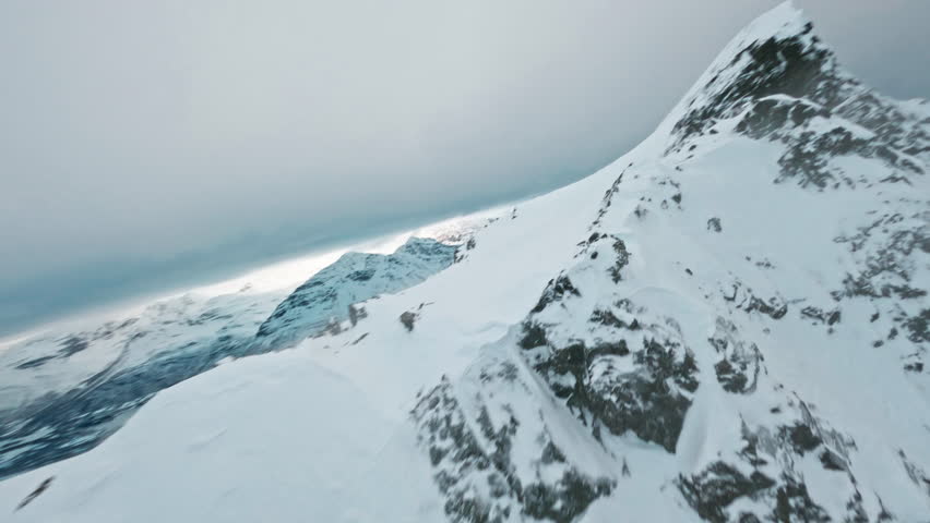 Snow-covered mountain peak in Tromsø fjords under cloudy winter sky