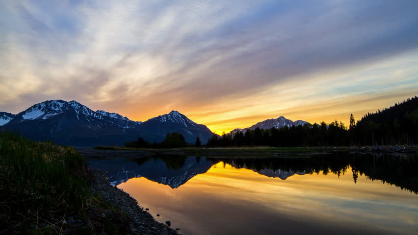 Lockdown Time Lapse Reflection Of Snowcapped Mountains In Lake Under Orange Cloudy Sky At Sunset - Seward, Alaska