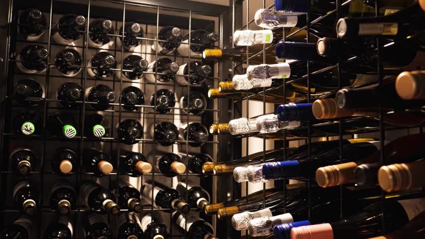 Variety Of Wine Bottles On Racks At A Restaurant. - wide shot