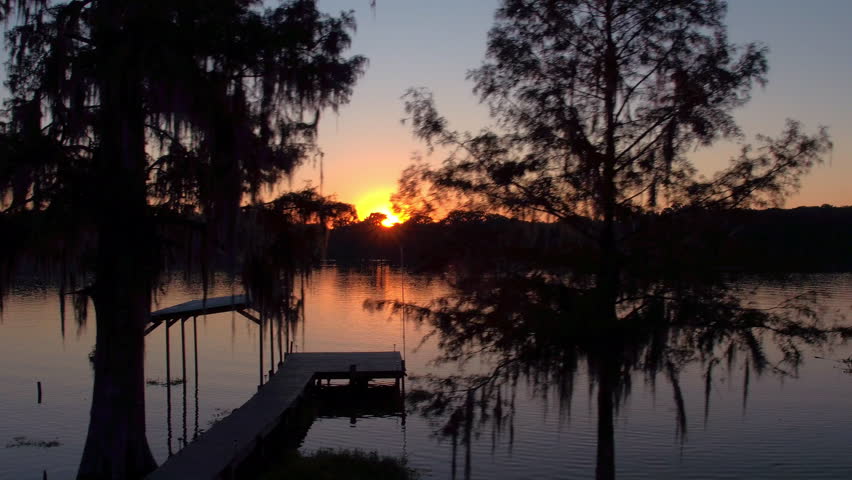 Aerial Panning Shot Of Empty Pier On Rippled Lakeshore, Drone Ascending Over Trees At Sunset - Bayou, Louisiana