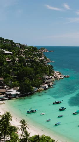 A scenic bay with turquoise water, small boats, and lush greenery along the shoreline. Koh Tao, Thailand.