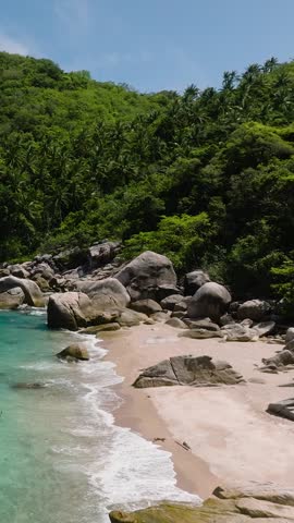 Turquoise bay surrounded by green hills and rocky shore under clear sky. Koh Tao, Thailand.