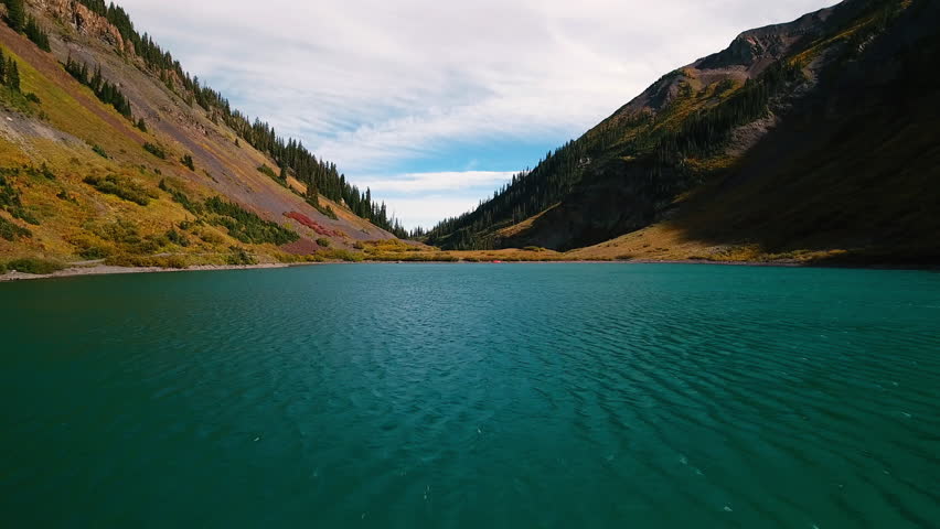 Aerial: Green Trees On Mountains Against Clouds, Drone Flying Forward Over Rippled Lake - CO, Colorado Springs, United States of America