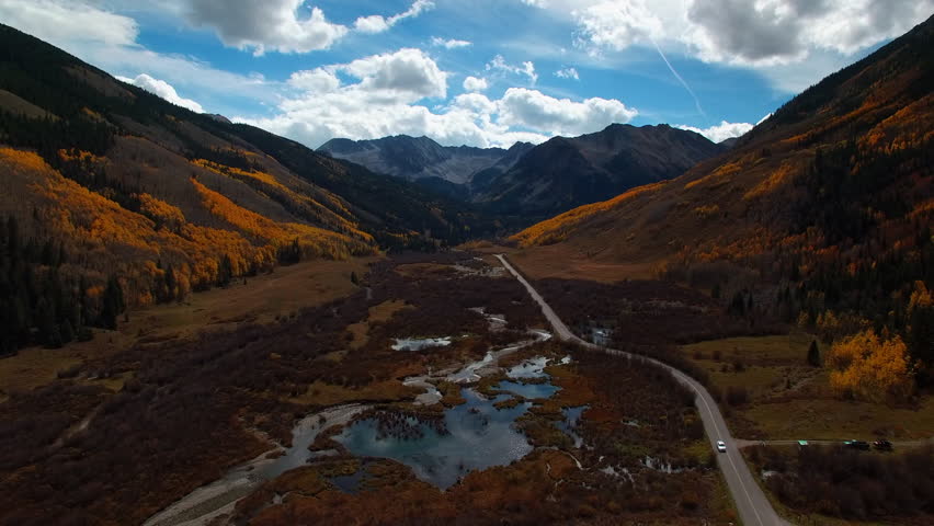 Aerial Backward Shot Of Car Moving On Road In Tranquil National Park Under Cloudy Sky - CO, Colorado Springs, United States of America