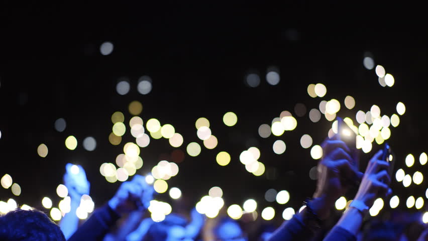 Many fun people lift hand up hold cell phone flash light. Fan crowd wave flashlights. Epic live music concert atmosphere. Big open air k pop arena. Cool night fest. Lot joy men hang out. Kpop chill.