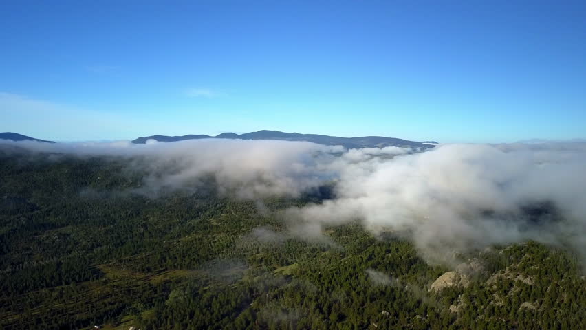 Aerial Shot Of Clouds Moving Over Green Forest On Mountains, Drone Flying Backwards During Sunny Day - CO, Colorado Springs, United States of America