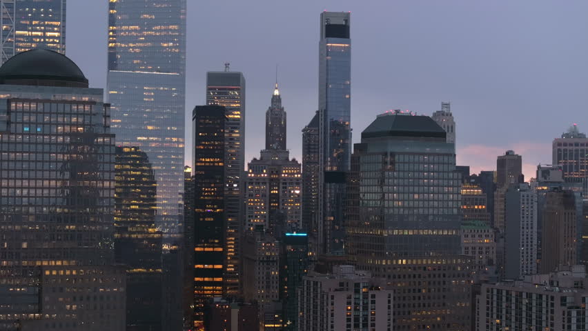 New York City Financial District glowing warmly in Lower Manhattan, skyscrapers lighting up during evening twilight hours