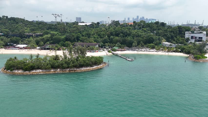 Flight along Siloso beach with palm trees and bars at Sentosa Island and cable car and skyline of Singapore in the background