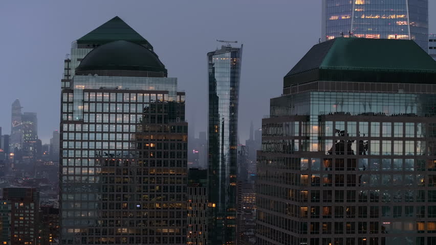 Brookfield Place shopping center and office building complex glowing with twilight city lights in Lower Manhattan, sweeping aerial view