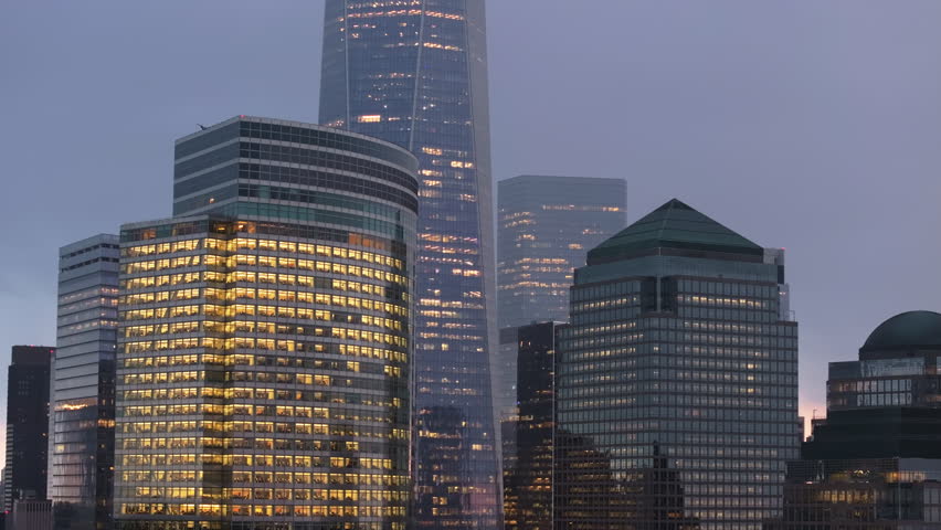 Aerial close up of Lower Manhattan skyscrapers glowing brightly, illuminating financial district